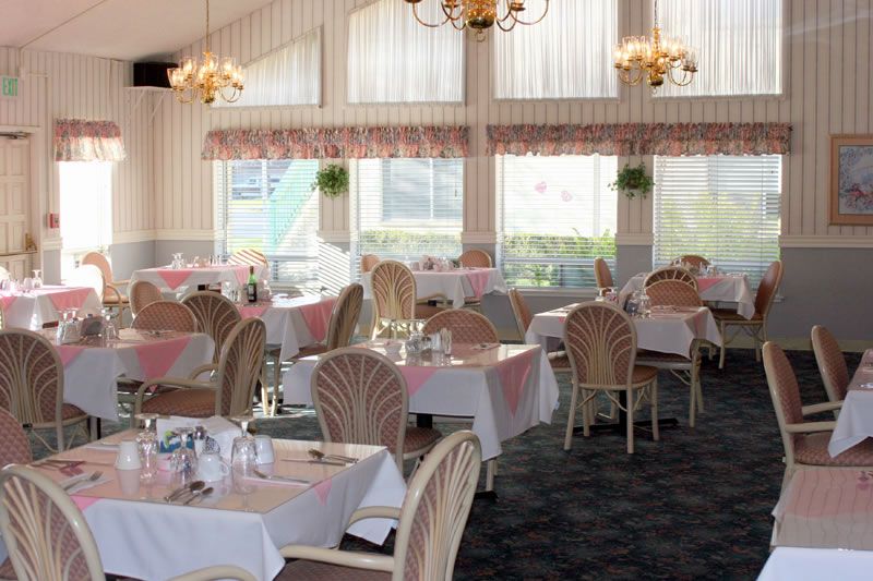 Elegant restaurant dining area with well-set tables and chandeliers.