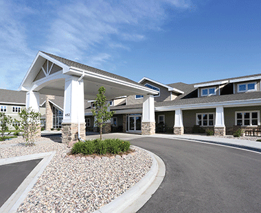 A modern residential building with a covered entrance and circular driveway.
