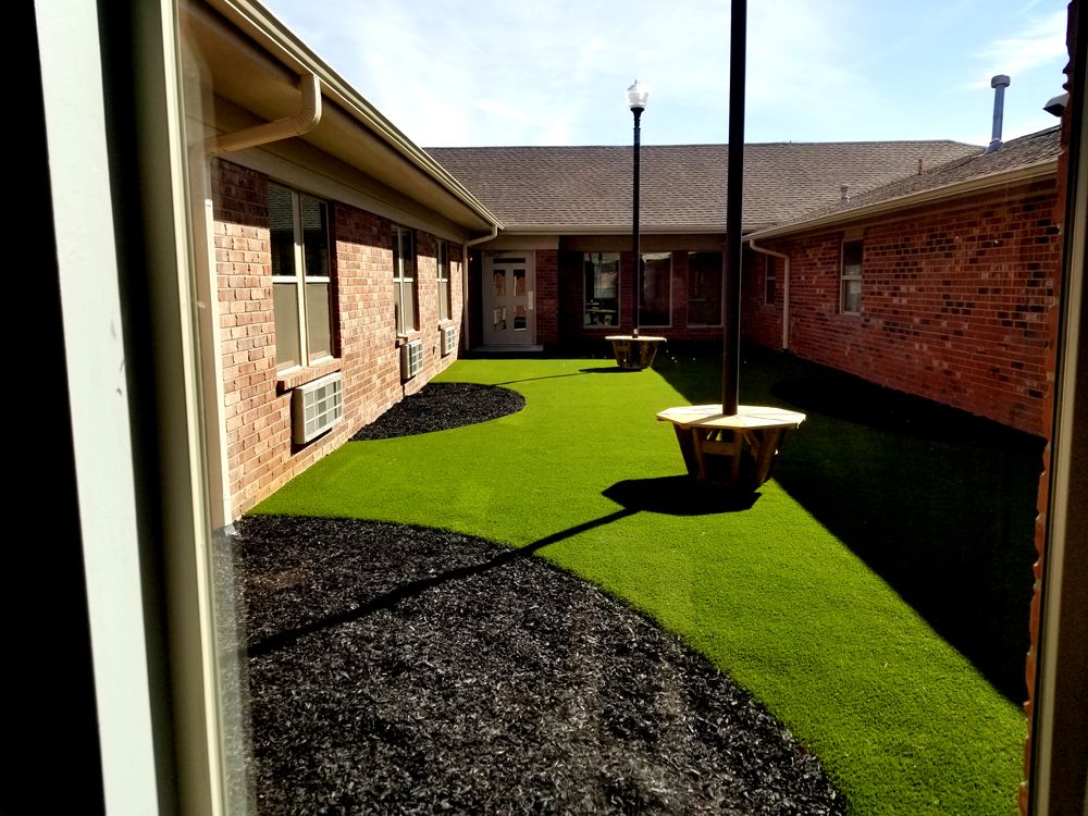 A courtyard with artificial grass and brick walls.