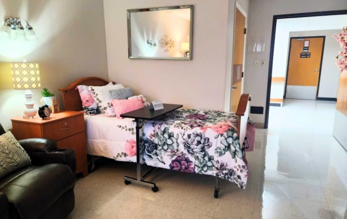 A well-decorated hospital room with a floral-themed single bed and an overbed table.