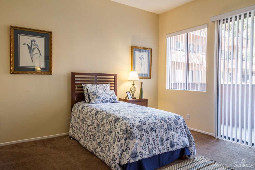 A cozy bedroom with a single bed and natural lighting from a window.