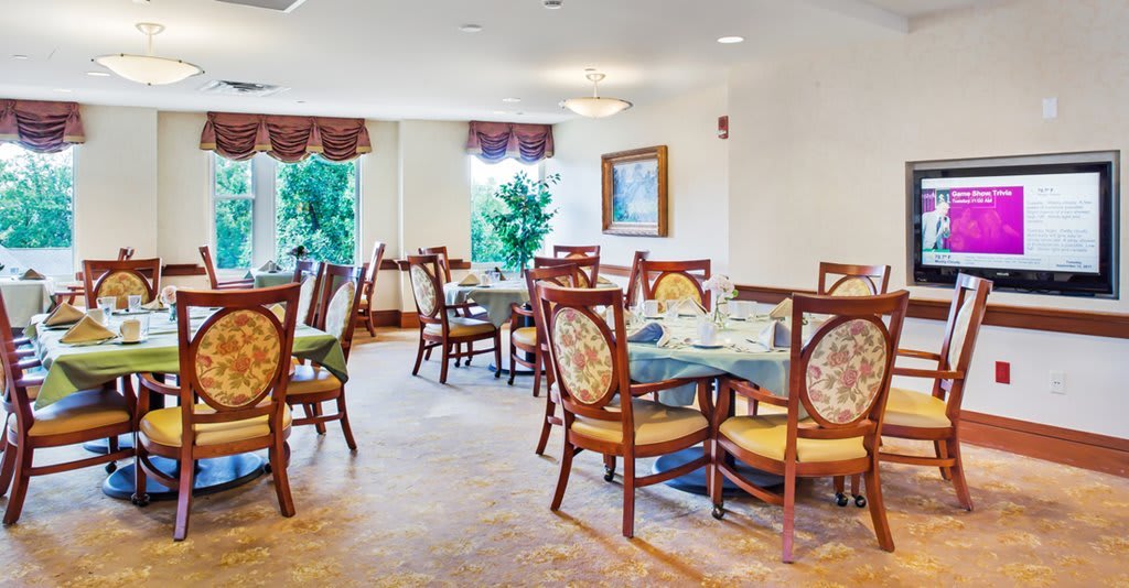 A cozy dining room with elegantly set tables and chairs near large windows.
