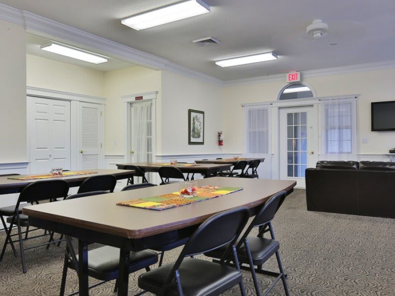 A spacious meeting room with multiple conference tables and chairs set up for a gathering.
