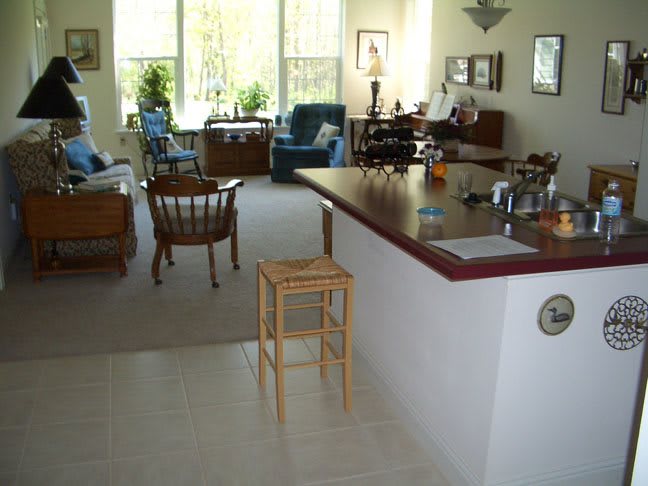 A cozy living area with a kitchen counter and natural light streaming through large windows.