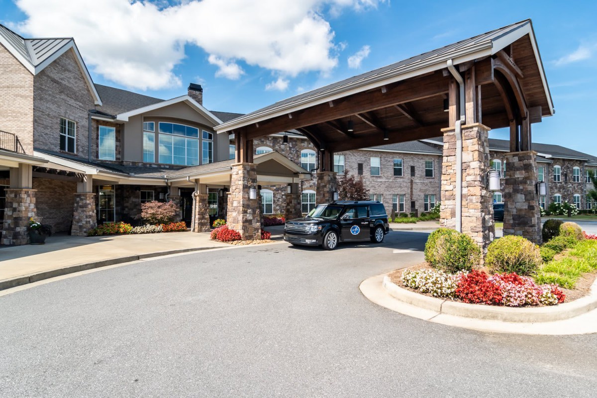 A car parked under the entrance of a large building with stone and wood architectural details.