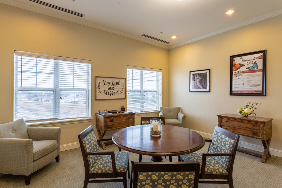 A cozy living room with a round table surrounded by chairs and elegant decor.