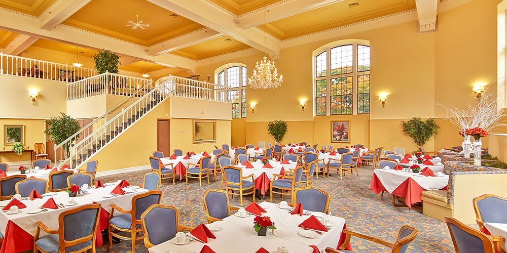 Elegant dining hall with neatly arranged tables and a grand chandelier.