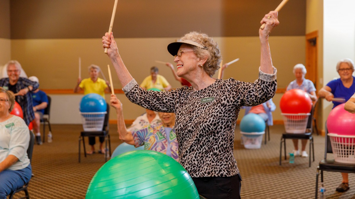 A group of seniors participating in a drumming exercise class.