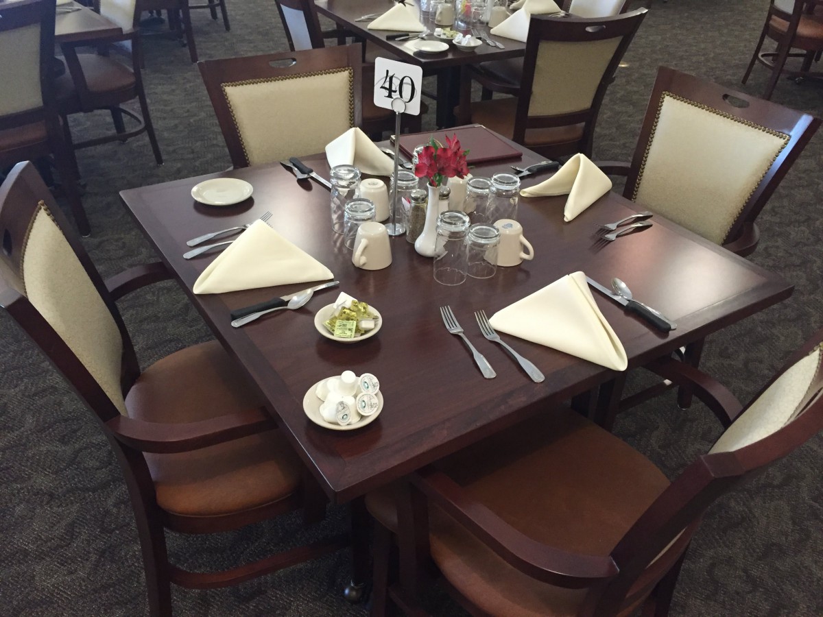 A neatly set dining table with napkins, cutlery, and water glasses in a restaurant.