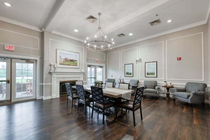 A beautifully designed dining room featuring a central table with chairs, elegant chandelier, and classic decorations on hardwood flooring.