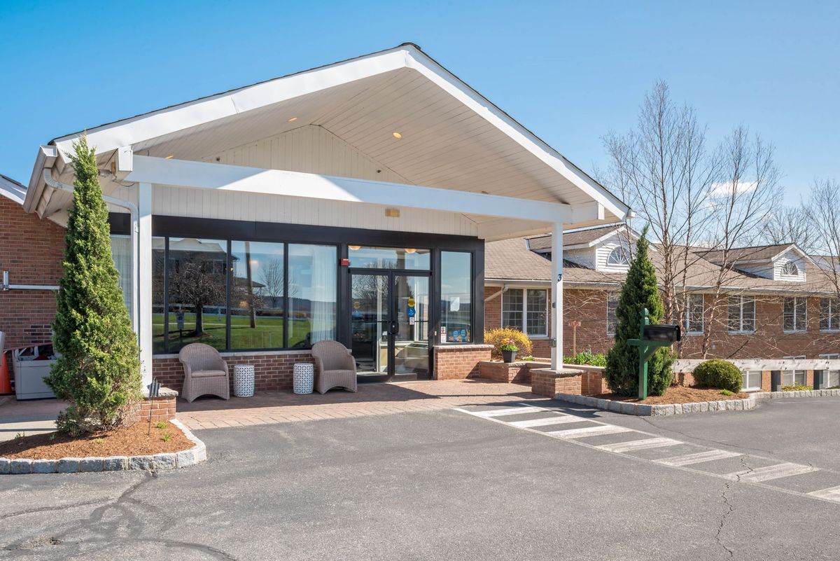 A modern building entrance with a covered canopy and landscaped surroundings.
