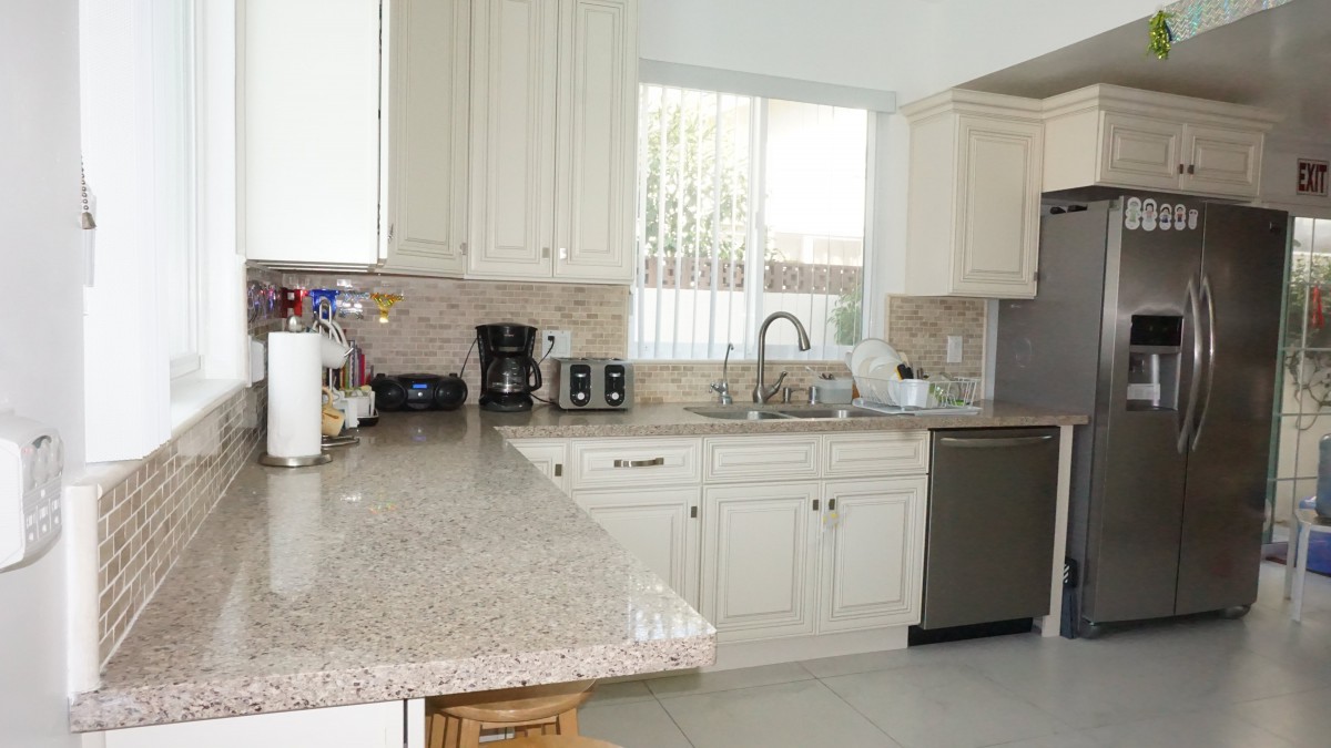 A modern kitchen with white cabinets and granite countertops.