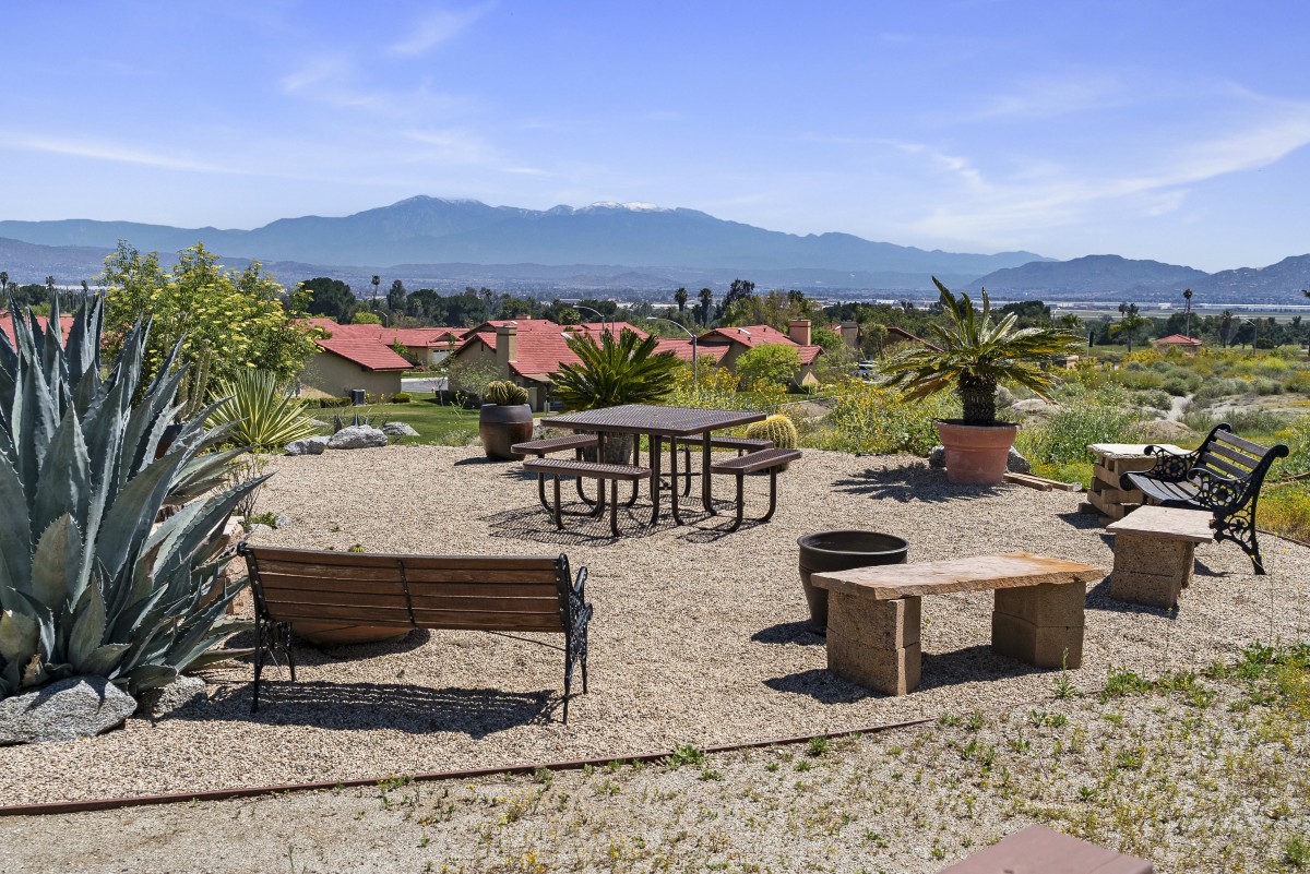 A scenic outdoor seating area with benches and tables overlooking a mountain range.