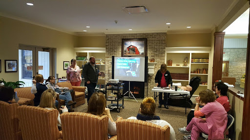 A community health workshop in progress, with a presenter demonstrating techniques to an engaged audience.