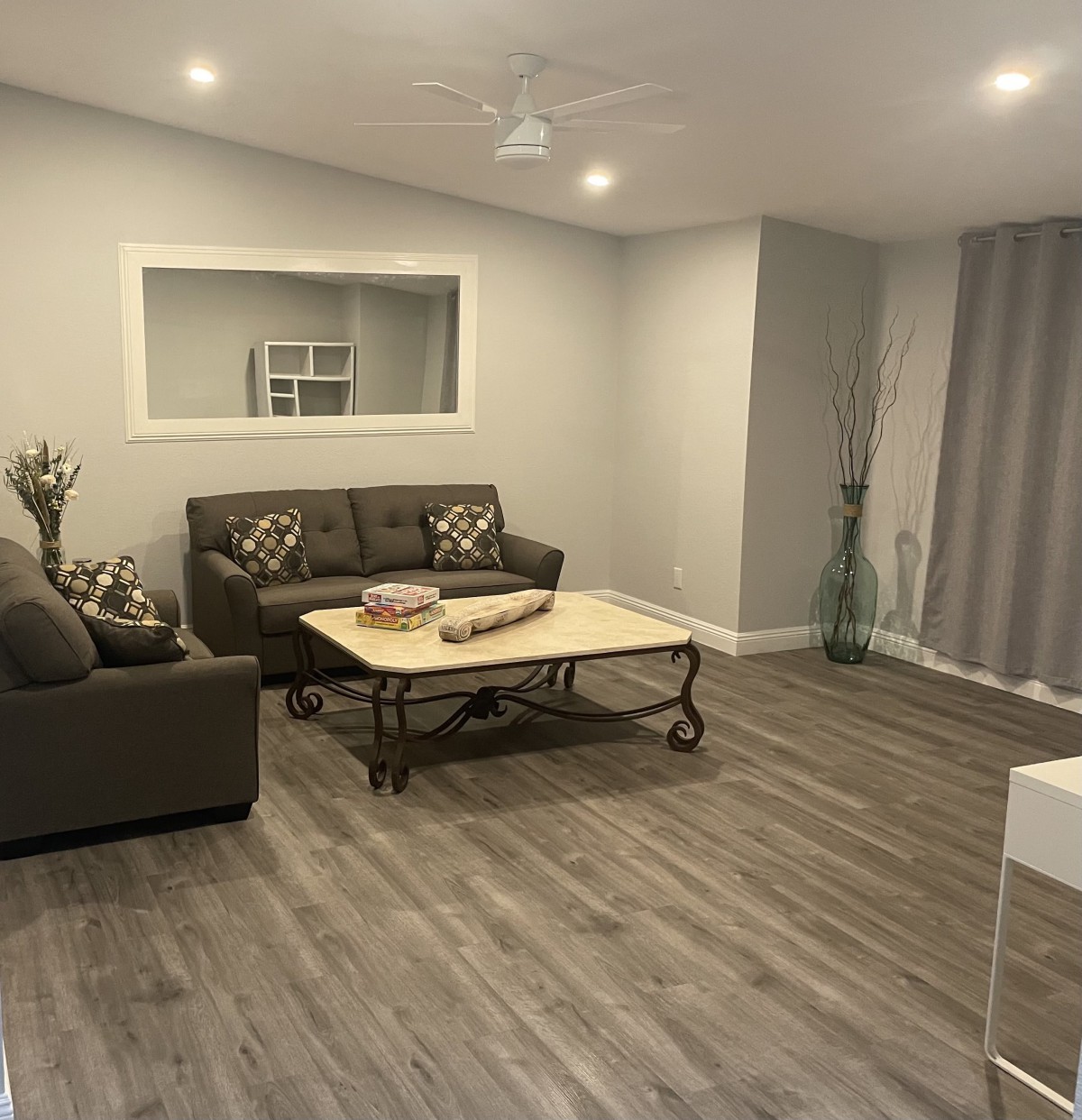 A modern living room with neutral tones, featuring a comfortable sofa and a sleek coffee table on wood flooring.
