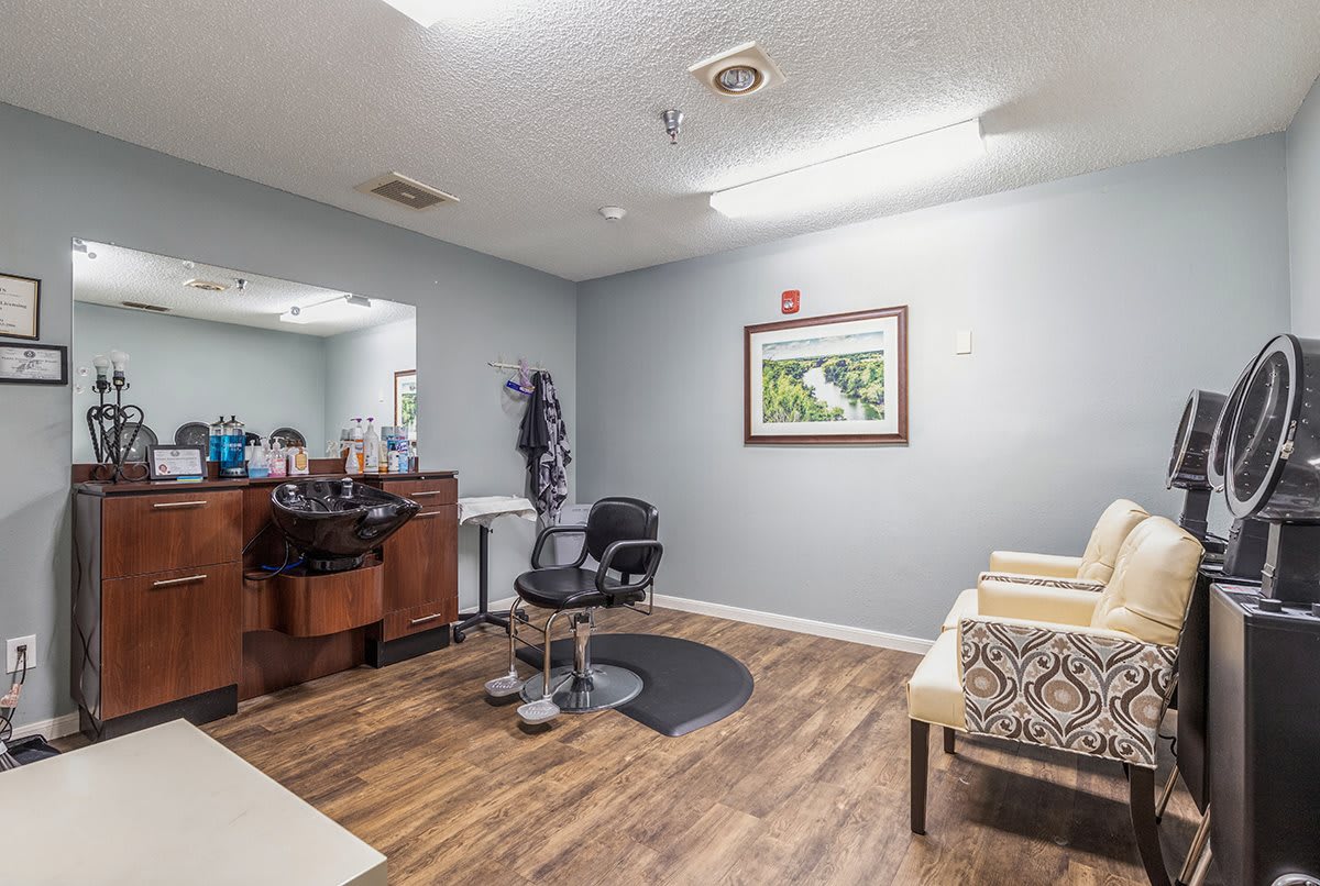 A modern hair salon interior with a barber chair, wooden floor, and decorative wall art.