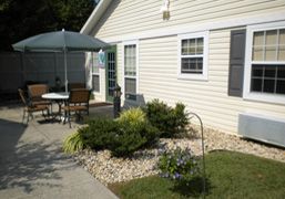 A patio area with outdoor furniture and landscaping in front of a house.