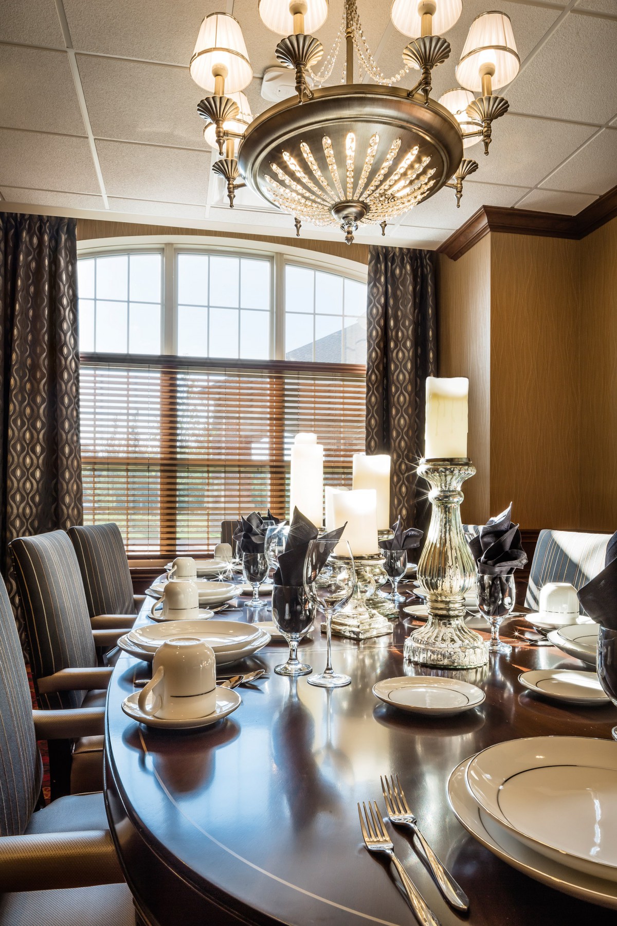 An elegantly set dining table with candles and fine dinnerware in a well-decorated room.