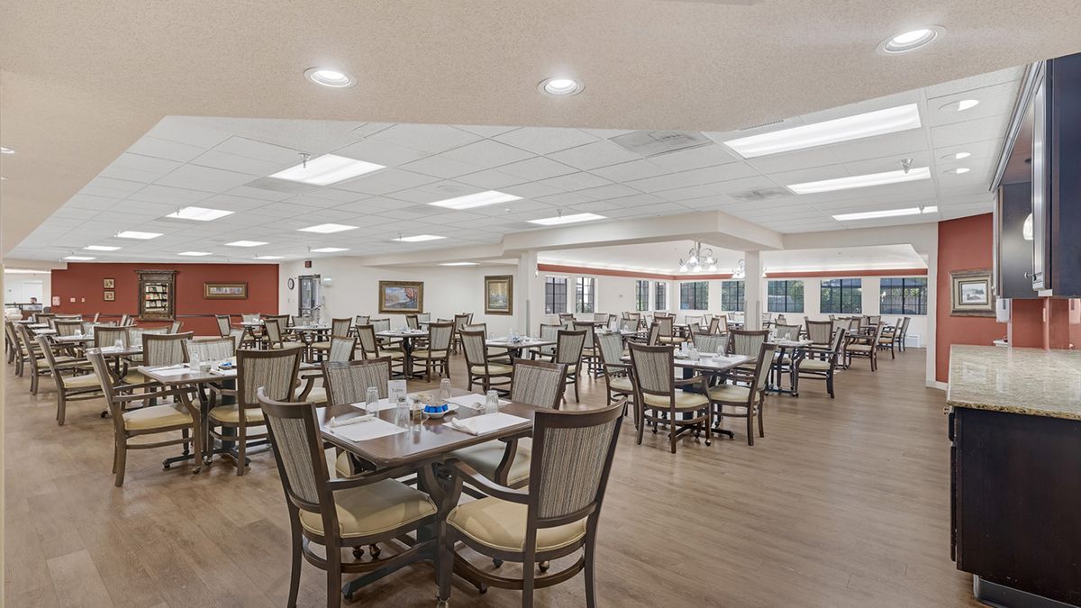 An empty restaurant dining room with neatly arranged tables and chairs under bright lighting.