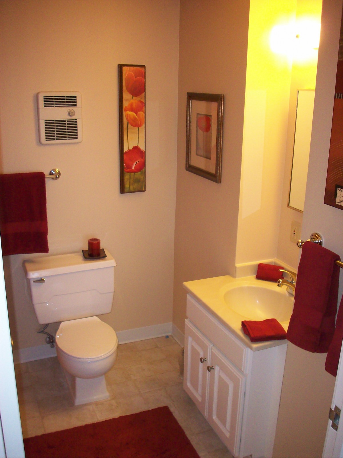 A neatly arranged bathroom featuring red accents and wall art.