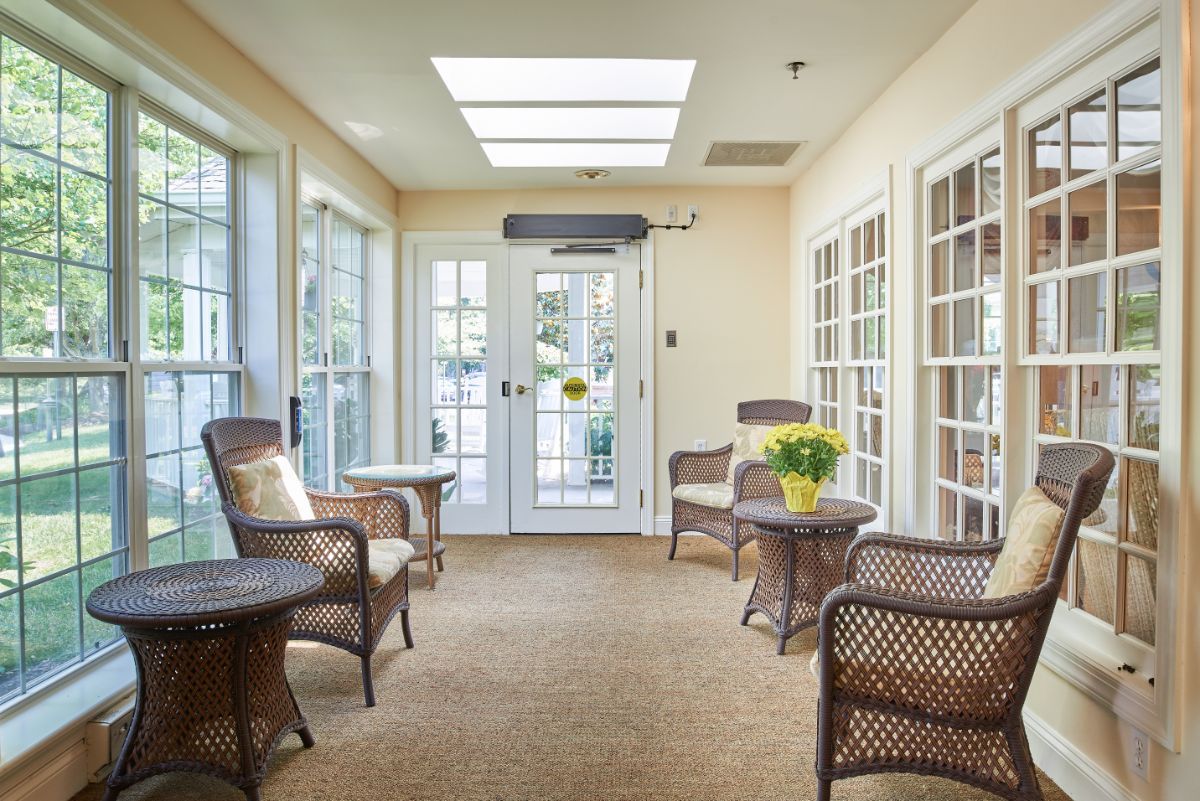A cozy sunroom featuring wicker furniture, large glass doors, and a skylight that allows natural light to fill the space.