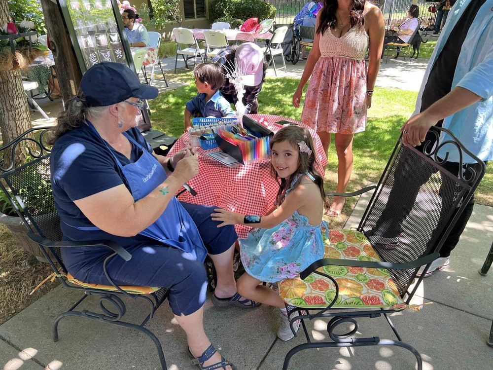 A joyful outdoor birthday party where children gather around to open gifts surrounded by family and friends.