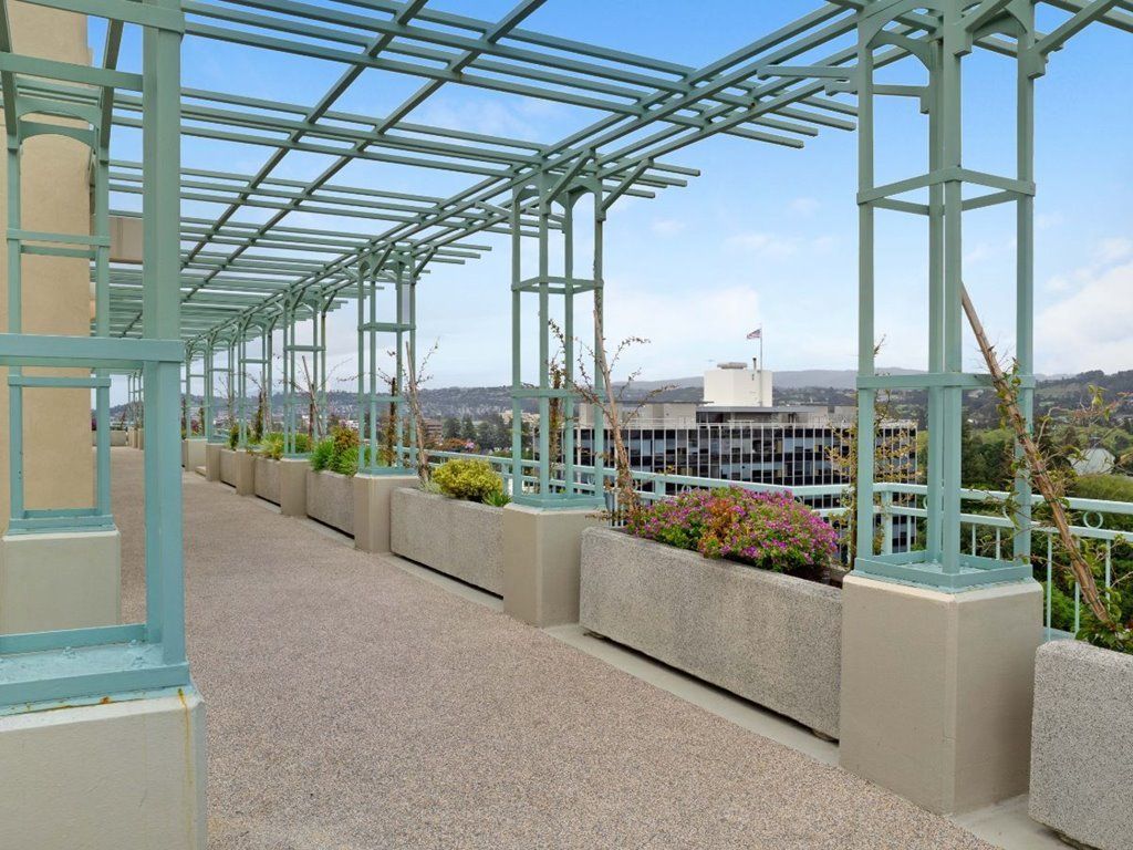 A modern rooftop terrace featuring a pergola with views of the urban landscape.