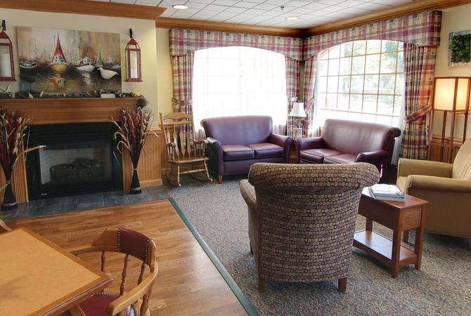 A cozy living room with sofas, a fireplace, and large windows allowing natural light.