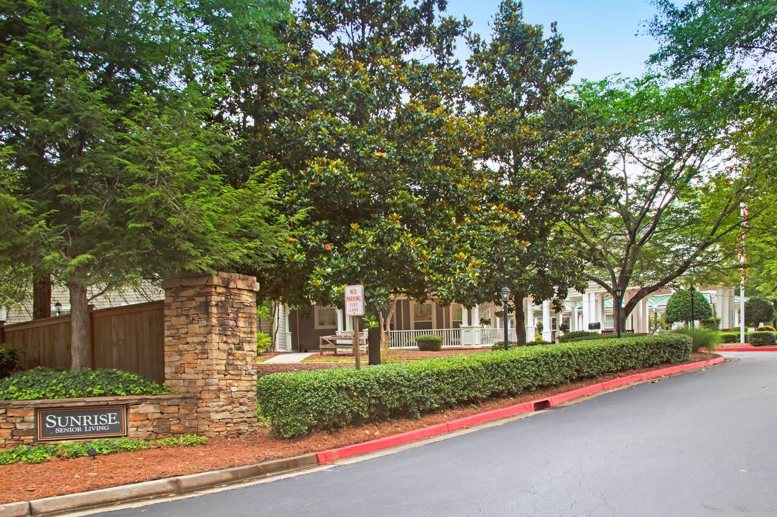 A scenic view of a road lined with trees and a building in the background.