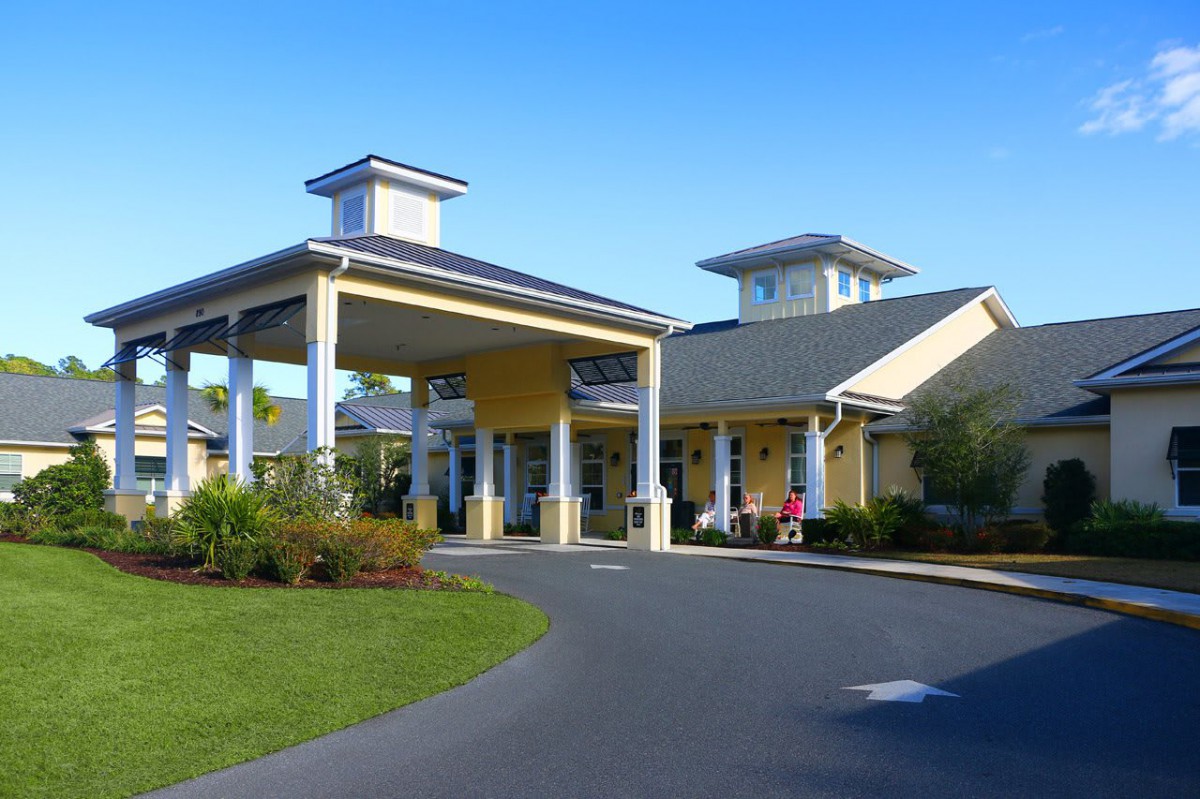 A well-maintained building with a covered entrance, surrounded by landscaped greenery.