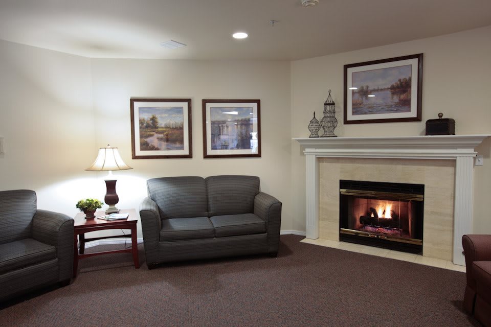 A cozy living room with a fireplace, sofa, and decorative artwork on the walls.