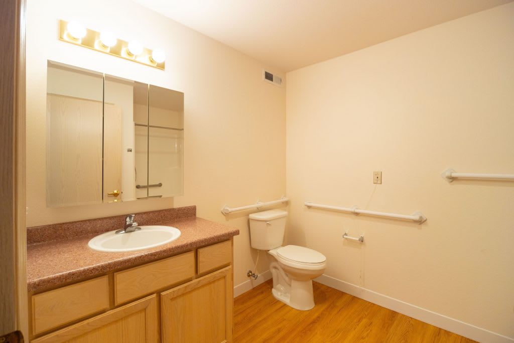 A clean and simple bathroom with a sink, toilet, and mirror.