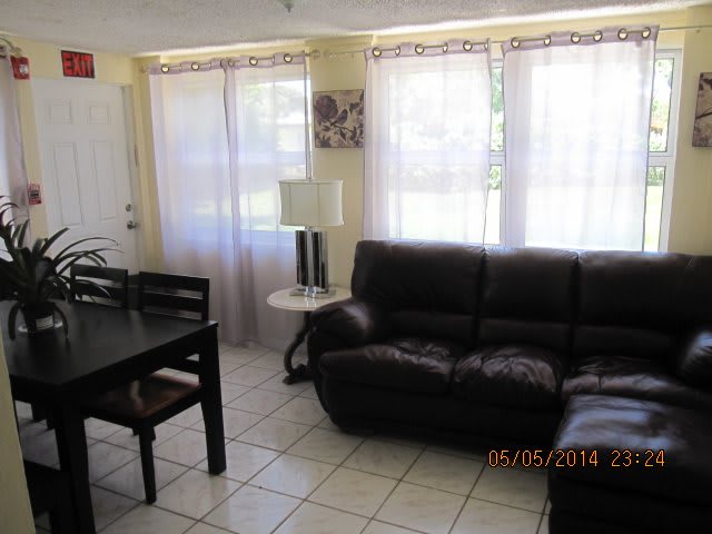 A cozy living room with a sofa, dining table, and large windows.