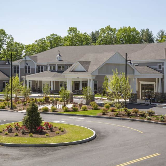 A large residential building with a landscaped driveway and surrounding greenery.