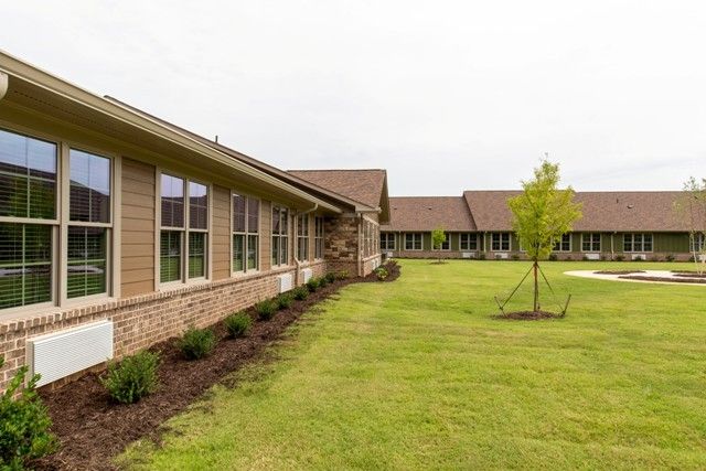 A view of a modern building with large windows and a well-maintained lawn.