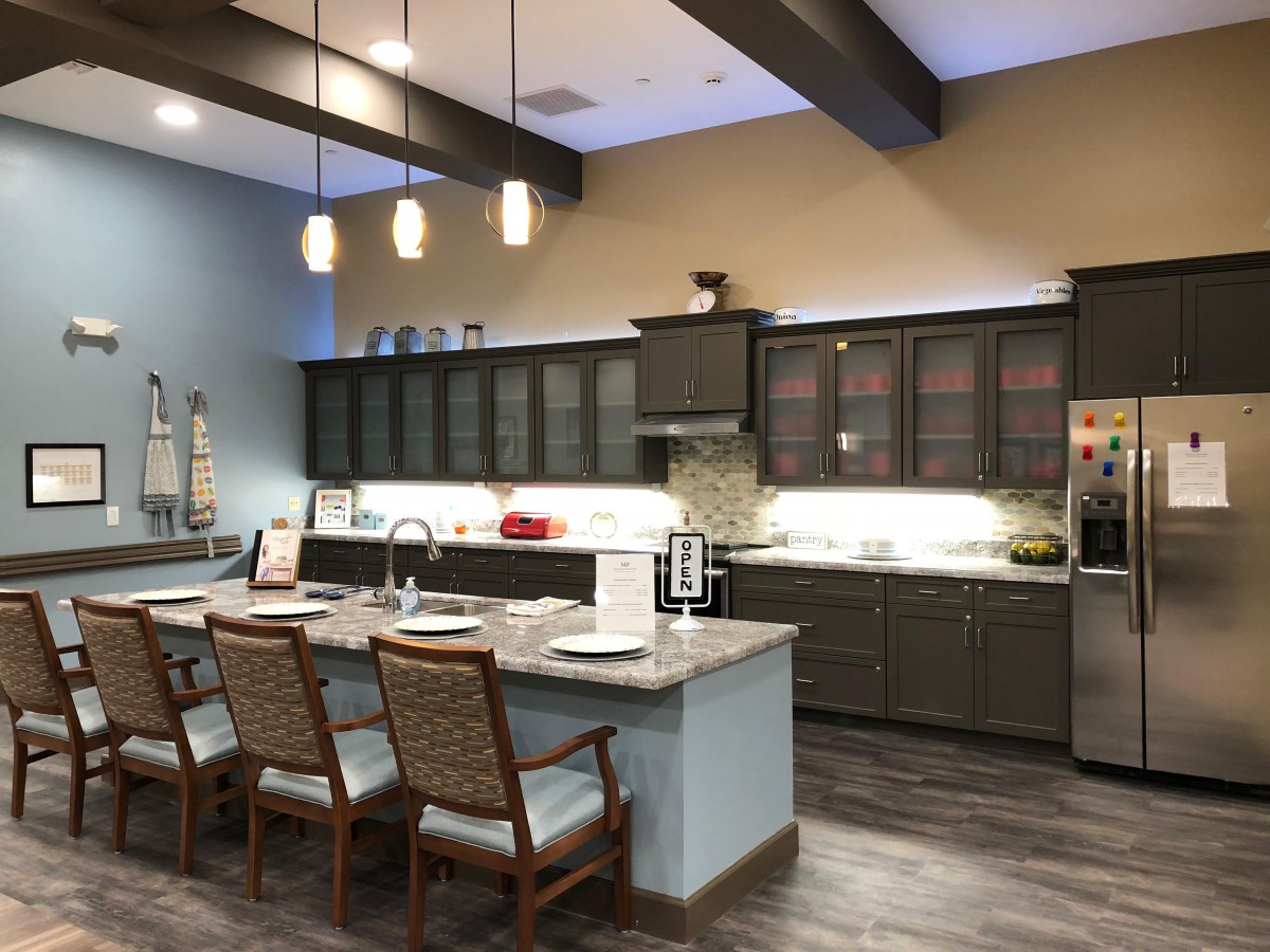 A modern kitchen with a central island, seating, and stylish lighting.