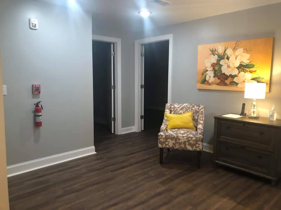 A cozy interior space with a decorative chair, lamp, and wall art.