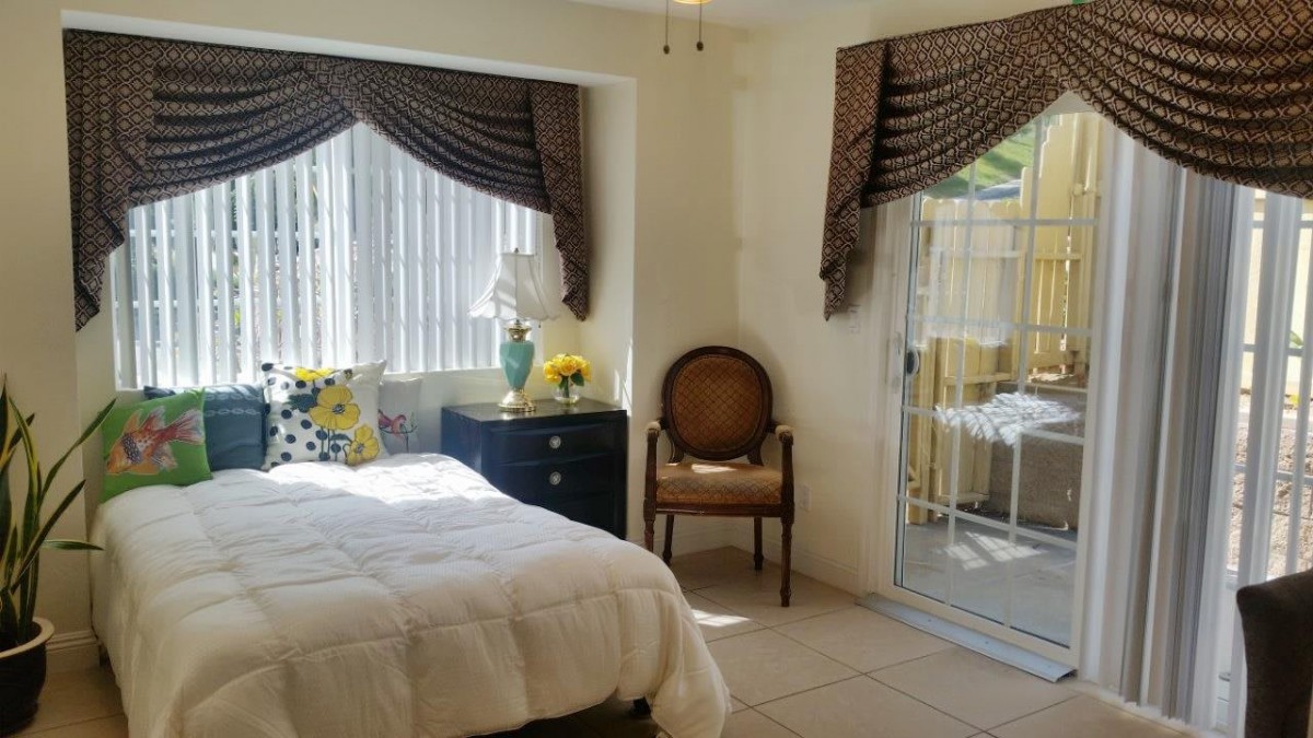 A cozy bedroom featuring a bed with white bedding, elegant curtains, and a comfortable chair by the window.