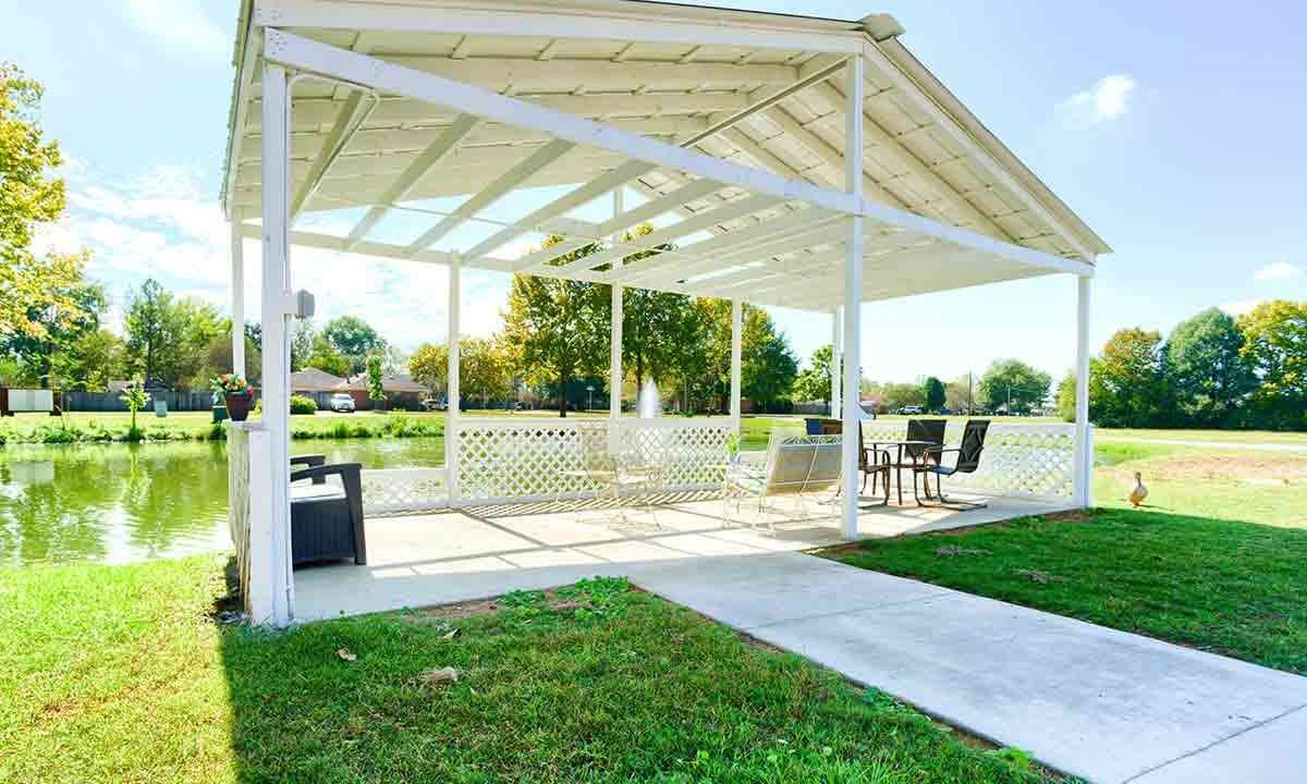 A beautiful outdoor gazebo with patio furniture, set against a lush green lawn on a sunny day.