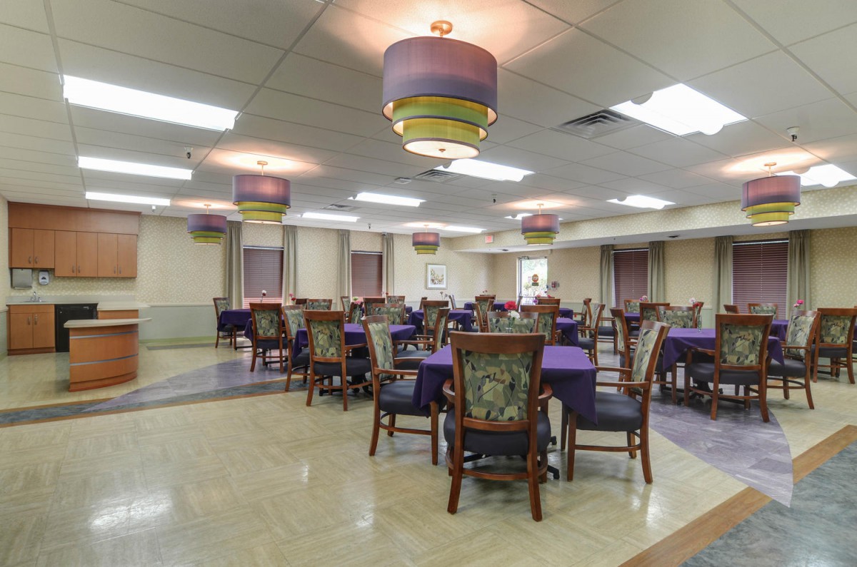 An empty dining hall with multiple tables and chairs arranged neatly.
