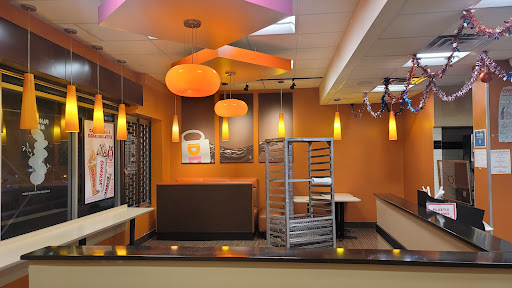 A modern restaurant interior featuring warm orange tones and contemporary lighting.