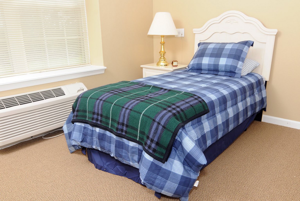 A neatly made bed with plaid bedding in a cozy bedroom setting.