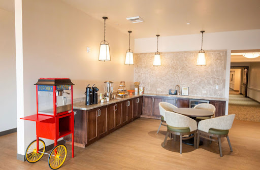A contemporary kitchen and snack area featuring a coffee machine, popcorn machine, and cozy seating.