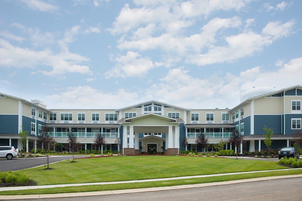 A modern residential building with a well-maintained lawn under a partly cloudy sky.