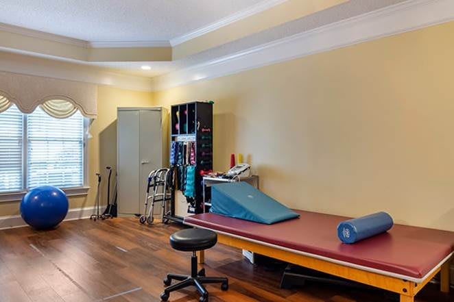 A well-equipped therapy room with a treatment table and exercise tools for rehabilitation.