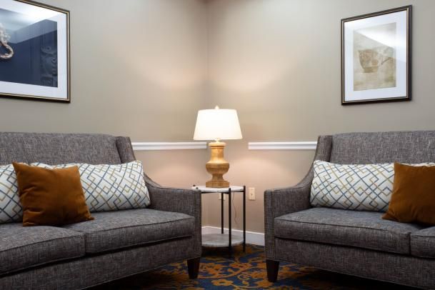 A cozy living room setup featuring two armchairs with a lamp on a small table in between.