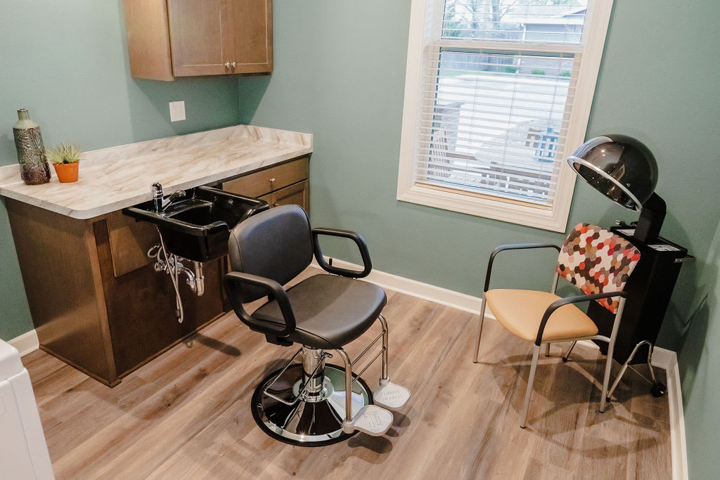 A clean and modern hair salon setup with a salon chair, sink, and window.