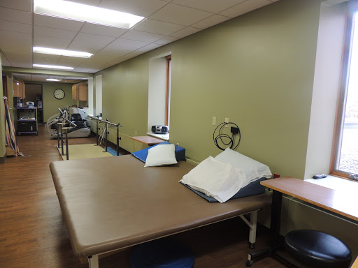 A spacious therapy room equipped with various rehabilitation tools and tables, designed for patient treatment.