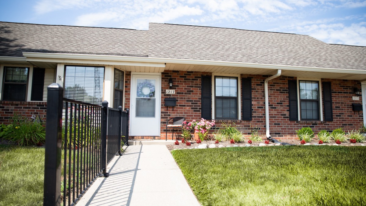 A brick residential house with a small garden in the front yard.