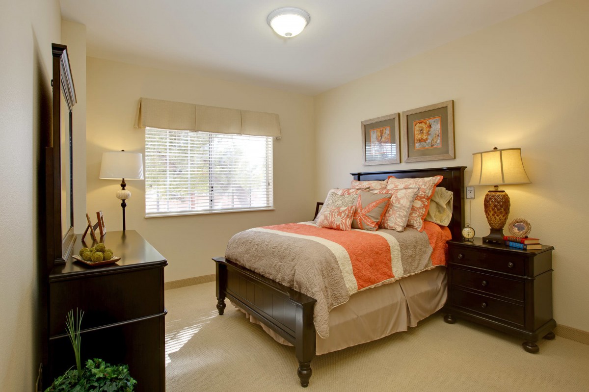 A cozy bedroom with a neatly made bed, bedside tables, and warm lighting.